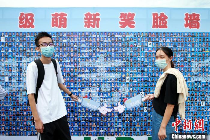 一名学生在“笑脸墙”上找到自己后合影留念 杨东 摄 一名学生在“笑脸墙”上找到自己后合影留念 杨东 摄