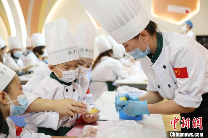 工作人员正在指导小朋友和家长制作月饼。　于晶 摄