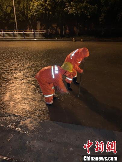 图为工作人员正在连夜消除道路积水点。　重庆市住房和城乡建设委员会供图