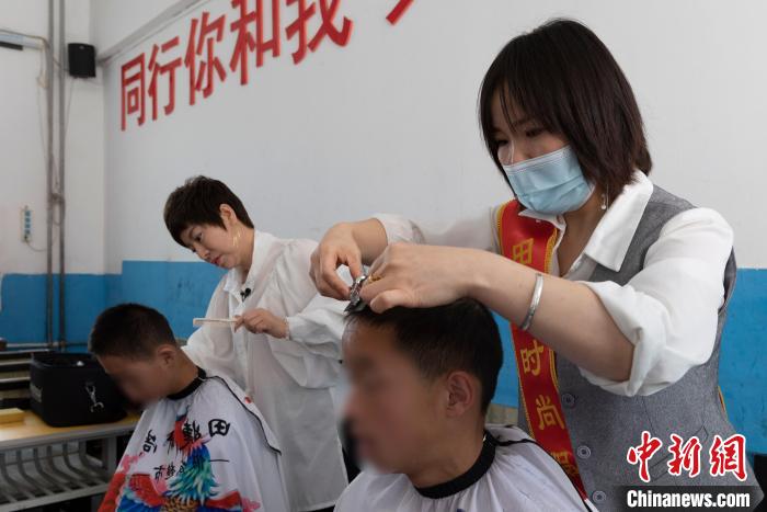 理发师田婕(左)正在和员工为残障儿童剪头发。 杨迪 摄 理发师田婕(左)正在和员工为残障儿童剪头发。 杨迪 摄