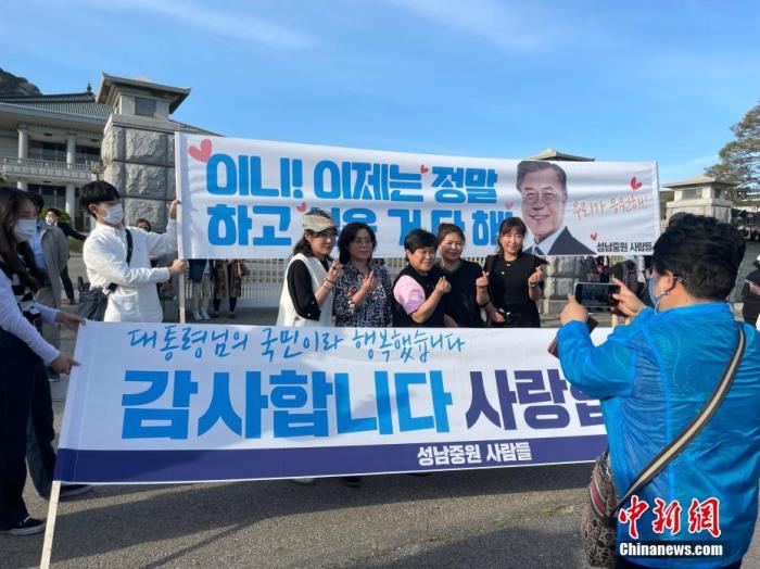 当地时间5月9日18时许(北京时间17时许)，韩国总统文在寅离开青瓦台。他的任期于当天午夜结束。图为民众在印有支持文在寅标语的横幅前合影留念。 <a target=
