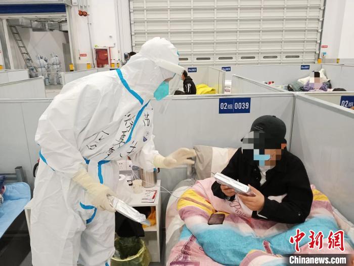 图为医护人员在方舱医院与患者沟通。 江苏省中医院供图 图为医护人员在方舱医院与患者沟通。 江苏省中医院供图