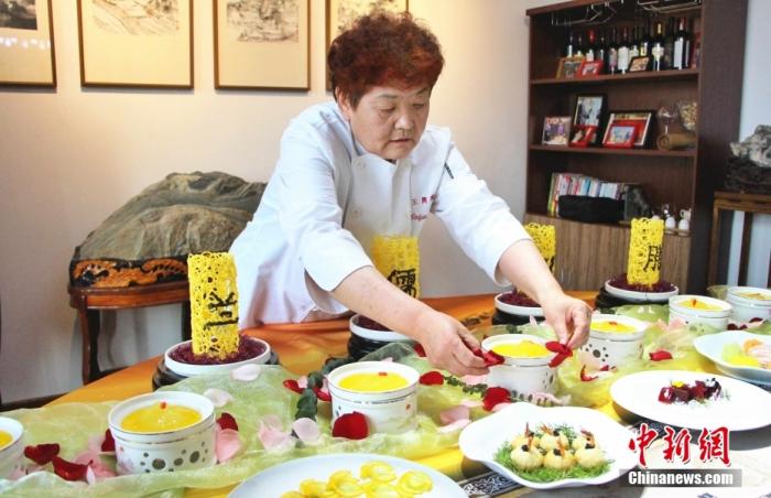 资料图为中国孔府菜首位女传人、山东省兰儒孔膳文化研究院院长王兴兰装点餐桌。 <a target= 资料图为中国孔府菜首位女传人、山东省兰儒孔膳文化研究院院长王兴兰装点餐桌。 <a target=