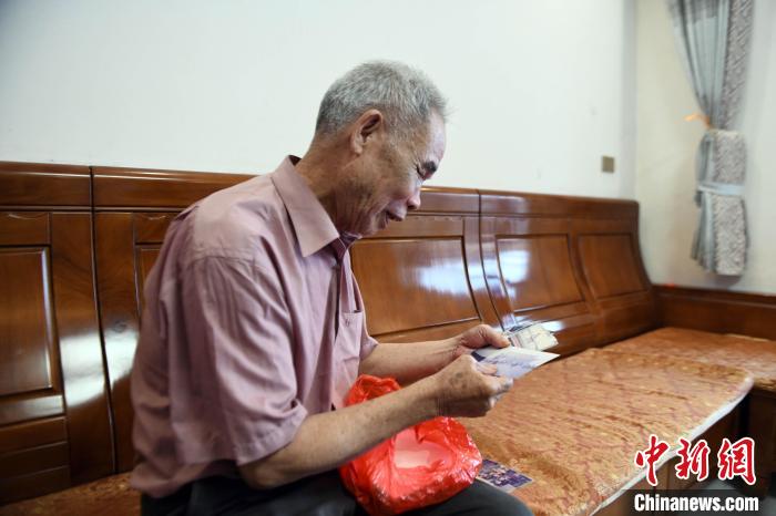 邓日辉拿出一本旧相册讲述生活变迁。　王猛 摄