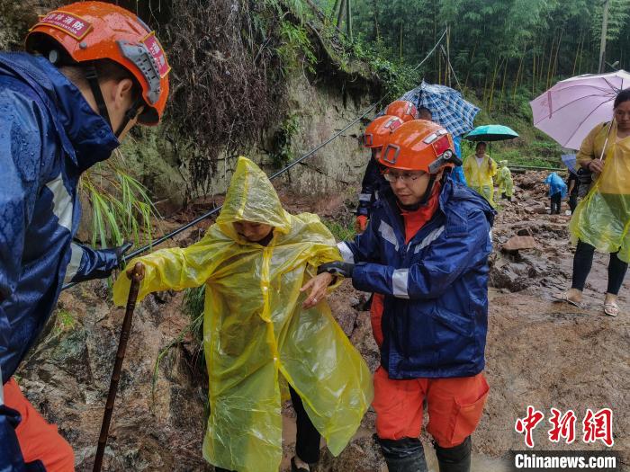 图为在地势陡峭地带,救援人员搀扶村民转移。 司寒杰 摄 图为在地势陡峭地带,救援人员搀扶村民转移。 司寒杰 摄