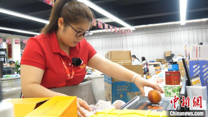 谢永敏开箱随机拿出一个桃子称重 韦杰夫 摄
