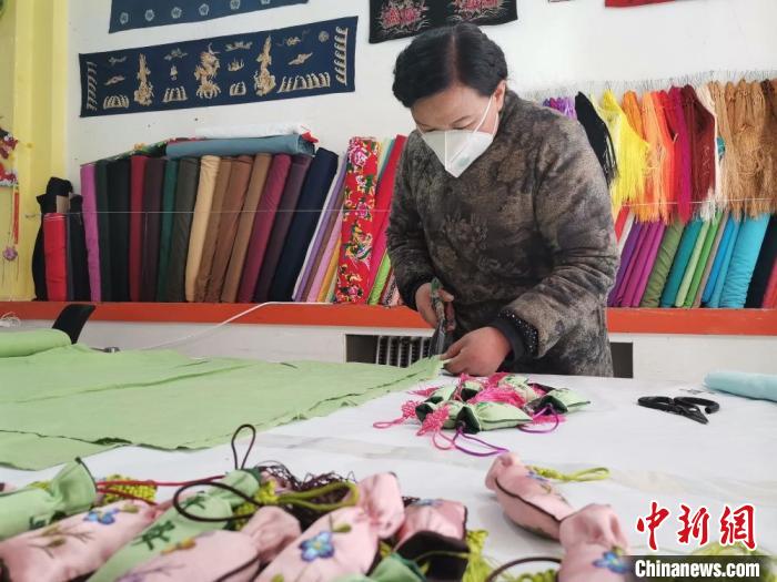 图为甘肃庆阳香包绣制传承人刘兰芳裁剪布料，用于制作防疫“平安香包”。(资料图) 甘肃省非物质文化遗产保护中心供图