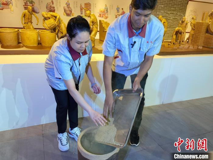 印度尼西亚在华留学生林精美(左)和孟加拉国在华留学生谢民在体验制作酱醅。　吕子豪 摄