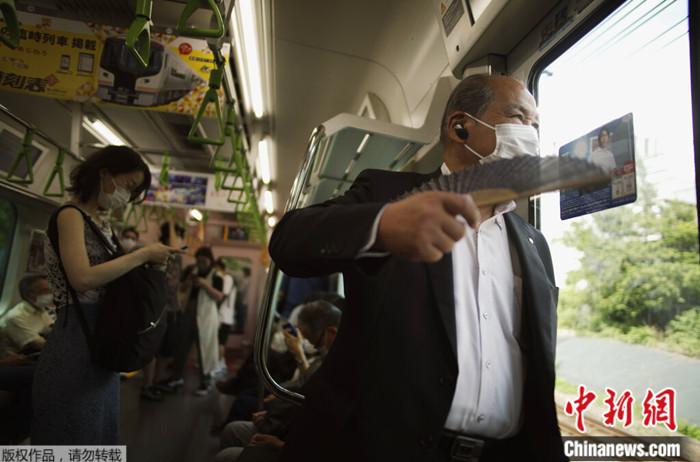 2022年6月27日，一名男子在东京乘坐火车时使用扇子扇风。日本政府27日警告东京地区可能出现电力短缺，并呼吁民众节约能源。